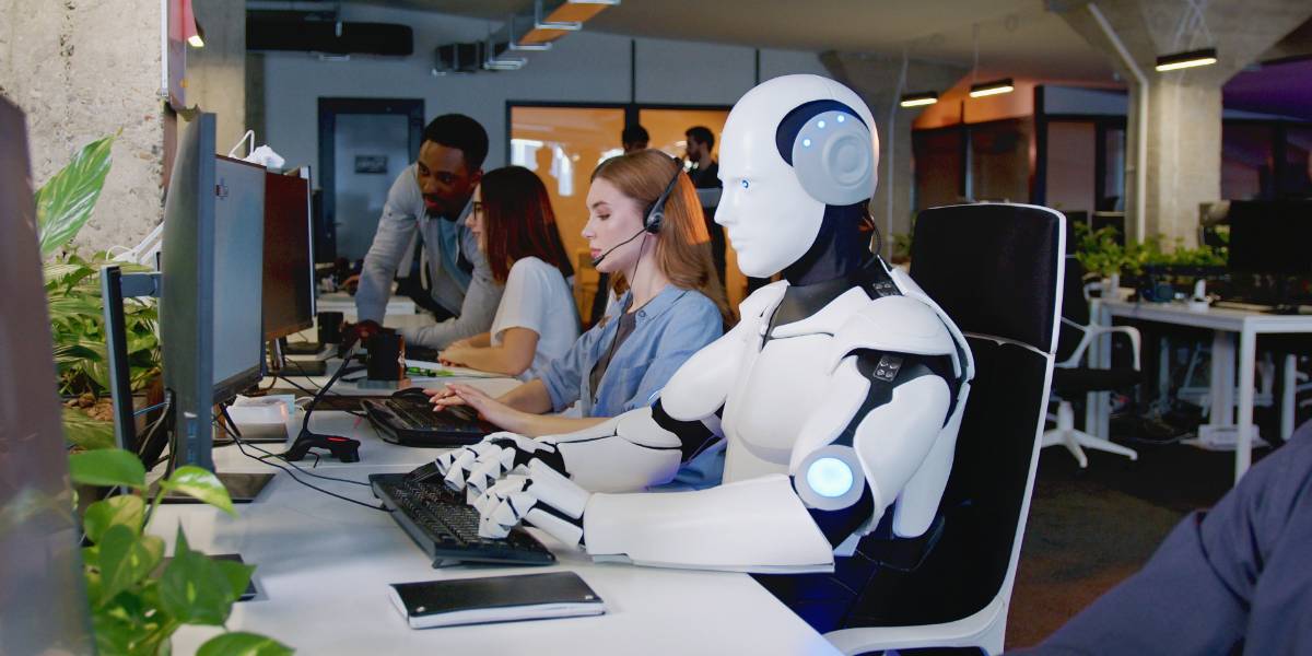 Foto de um ambiente de escritório moderno, onde um robô humanoide equipado com fones de ouvido trabalha em um computador ao lado de uma equipe humana. Uma mulher ao lado do robô também usa fones de ouvido, enquanto outras pessoas ao fundo colaboram em tarefas. O ambiente é preenchido com vegetação e tecnologia, simbolizando a integração de inteligência artificial e humanos no local de trabalho