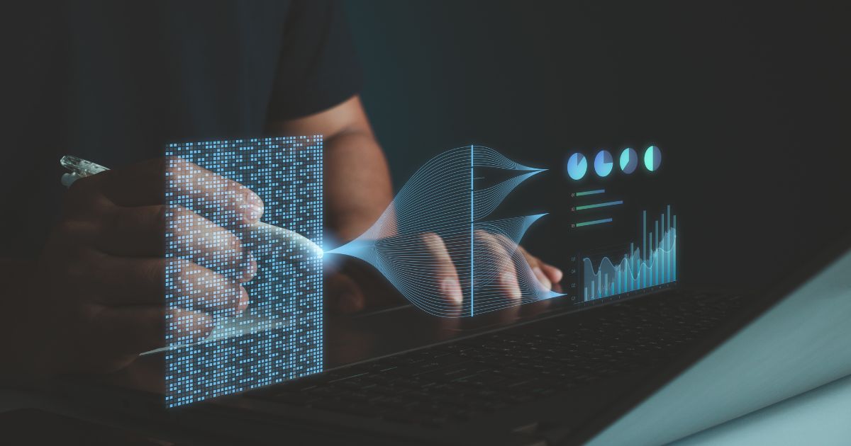 Uma pessoa segura uma caneta enquanto interage com um holograma digital que exibe dados e gráficos analíticos. A imagem tem um tom futurista, destacando um fluxo de dados que se conecta a um laptop, com elementos visuais representando análise de informações e tecnologia avançada. O fundo escuro contrasta com as luzes azuis e brilhantes do holograma.